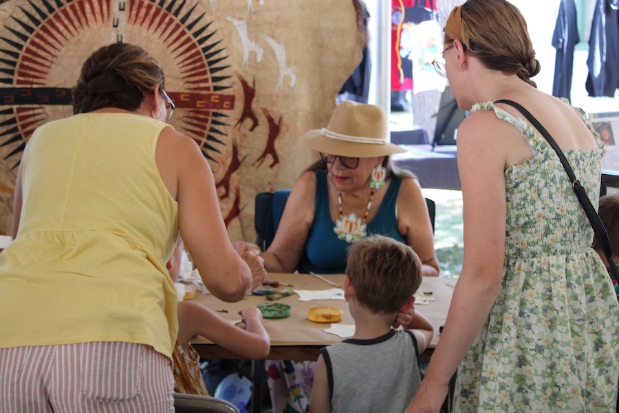 Fern Cloud, 2023 NAAIR Artist teaching traditional hide painting at Mille Lacs Art festival.